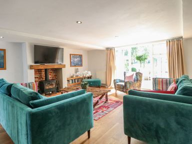 A living room with teal sofas a wood burning stove and a wooden coffee table at The Barn in Tunstead near Hoveton & Wroxham
