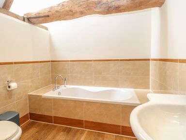 A bathroom with a bathtub toilet and sink at The Barn in Tunstead near Hoveton and Wroxham