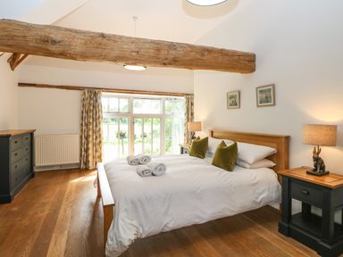 A bedroom with a wooden bed a chest of drawers and bedside tables at The Barn in Tunstead near Hoveton & Wroxham