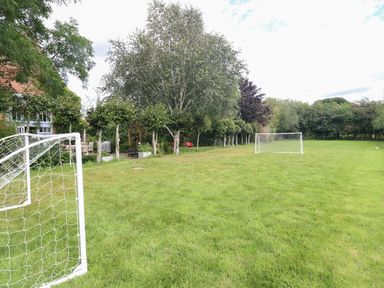 A large grassy garden with two white soccer goals and trees along the side at The Barn in Tunstead near Hoveton & Wroxham