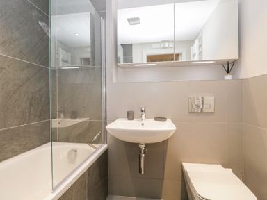A bathroom with a bathtub shower combination a wall mounted sink and a toilet at River View in Backbarrow