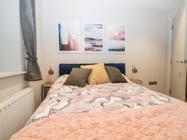 A bedroom with a bed featuring patterned bedding and cushions with bedside tables and lamps at River View in Backbarrow