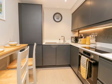 A kitchen with dark cabinets wooden stools a dining table and yellow kitchen appliances at River View in Backbarrow