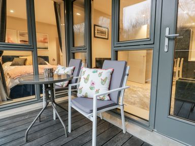 A small outdoor seating area with two chairs and a round table outside a room with a bed at River View in Backbarrow