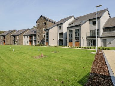 A grass lawn in front of modern apartment buildings at River View in Backbarrow
