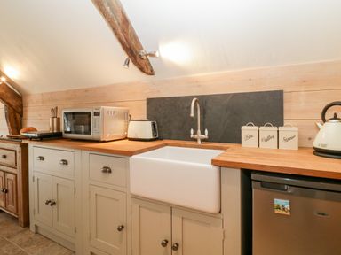 A kitchen countertop with a microwave toaster sink kettles containers with labels and a small fridge at The Barn at Rapps Cottage in Rapps near Ilminster