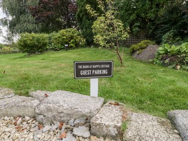 A sign on grass indicating guest parking at The Barn at Rapps Cottage in Rapps near Ilminster