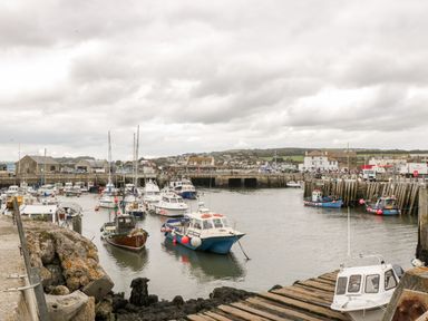 A harbor with boats docked and buildings in the background at The Barn at Rapps Cottage in Rapps near Ilminster