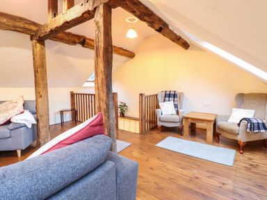 A living room with wooden beams two armchairs a wooden table and a gray sofa at Yr Hen Felin in Llanfyllin