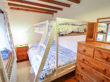 A bedroom with a bunk bed wooden dresser with mirror and bedside table at Yr Hen Felin in Llanfyllin