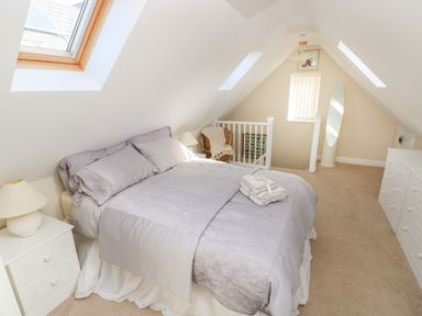 A bedroom with a bed side tables a chair a dresser and skylights at Ffau'r Ddraig in Cross Hands