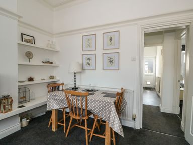A dining room with a table covered by a polka dot tablecloth and wooden chairs at Northgate Ground Floor Flat in Hunstanton