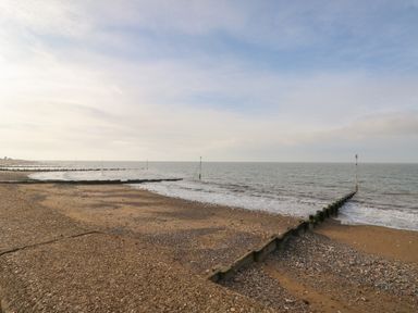 A beach with wooden groynes extending into the sea and a cloudy sky at Northgate Ground Floor Flat in Hunstanton