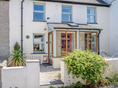 Front view of a two-story house with a small porch and windows with light blue frames at Sea Pickle Cottage in Llangwm Pembrokeshire