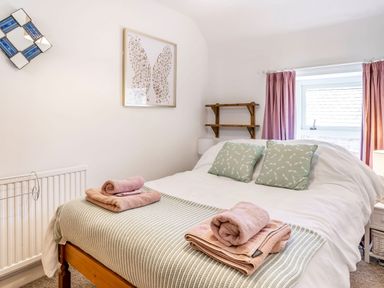 A bedroom with a bed made with green cushions and towels on the bed at Sea Pickle Cottage in Llangwm Pembrokeshire