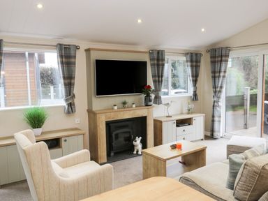 A living room with a fireplace television armchairs coffee table and large windows at Huckleberry in Runswick Bay near Staithes