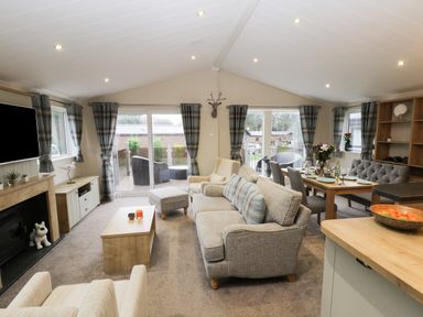 A living room with sofas a coffee table a dining table and chairs with a sliding door to outside at Huckleberry in Runswick Bay near Staithes