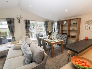 A living room with dining table set and sofa with plaid cushions at Huckleberry in Runswick Bay near Staithes