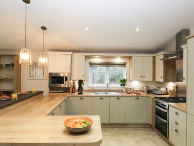 A kitchen with wooden countertops a stove microwave sink and fruit bowl at Huckleberry in Runswick Bay near Staithes