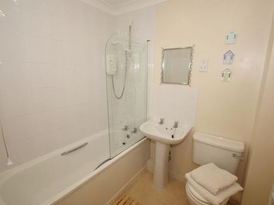 A bathroom with a bathtub shower combination sink toilet and small wall decorations at Waters Edge in Falmouth