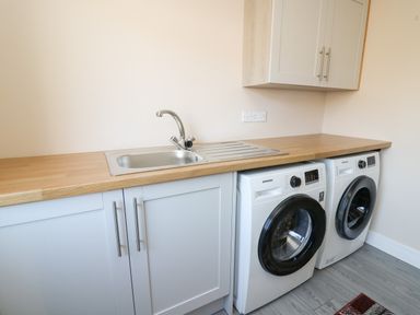 A laundry room with a sink countertop and two washing machines at Glyn Cottage in Llanon
