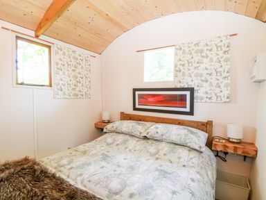 A bedroom with a bed with patterned bedding and two windows at Hugatree in Little Dunham near Litcham