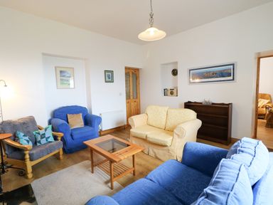 A living room with blue and yellow sofas a wooden coffee table and a wooden shelf unit at Ard an Phiobaire in An Luinnigh near Derrybeg County Donegal