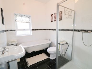 A bathroom with a bathtub toilet sink shower and a small table at Ard an Phiobaire in An Luinnigh near Derrybeg County Donegal