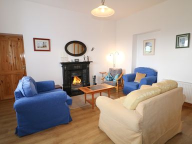 A sitting room with blue and beige armchairs around a fireplace at Ard an Phiobaire in An Luinnigh near Derrybeg County Donegal
