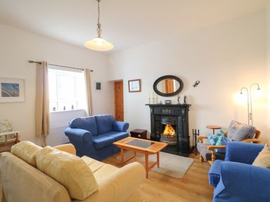 A living room with sofas around a fireplace and a wooden coffee table at Ard an Phiobaire in An Luinnigh near Derrybeg County Donegal