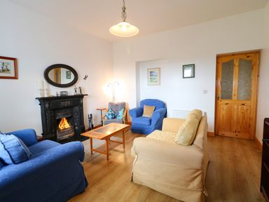 A living room with armchairs a fireplace a wooden door and a coffee table at Ard an Phiobaire in An Luinnigh near Derrybeg County Donegal