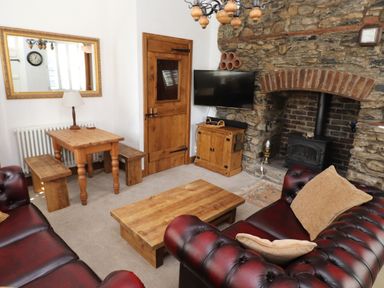 A living room with leather sofas wooden coffee table fireplace and dining table at The Old Carriage House in Clappersgate