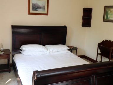 A bedroom with a wooden bed and white bedding two bedside tables and framed pictures on walls at The Old Carriage House in Clappersgate