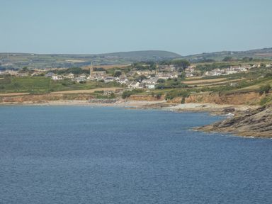 A coastal view with houses and fields behind a beach and sea at Kernyk in Perranuthnoe