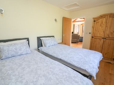 A bedroom with two single beds and a wooden wardrobe at Ploony Hill Cabin in Bleddfa near Knighton