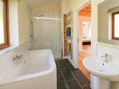 A bathroom with a bathtub shower sink and towel rack at Ploony Hill Cabin in Bleddfa near Knighton