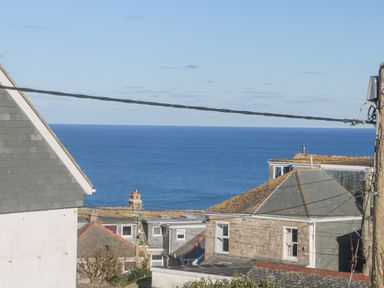 A view of rooftops and chimney stacks with the ocean in the background at The Beach Hut in St Ives