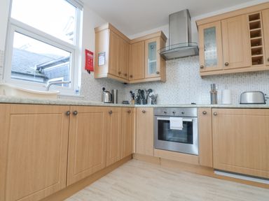 A kitchen with wooden cabinets a countertop oven and kitchen utensils at The Beach Hut in St Ives