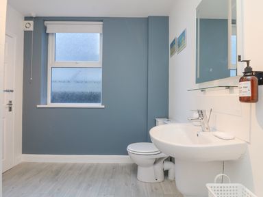 A bathroom with a toilet sink mirror and window at The Beach Hut in St Ives