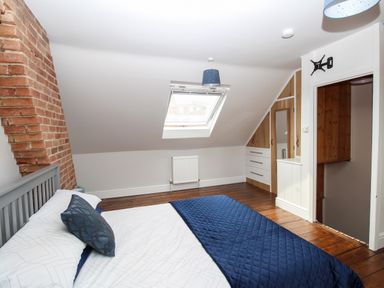 A bedroom with a bed a skylight window wooden floor and built-in wardrobes at Weybury Cottage Brewers Quay Harbour