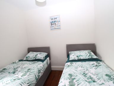 A bedroom with two single beds with leaf patterned bedding and a framed sign on the wall at Weybury Cottage in Brewers Quay Harbour