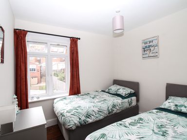 A bedroom with two single beds and a window with red curtains at Weybury Cottage in Brewers Quay Harbour