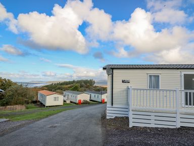 A group of static caravans on a hillside with a cloudy sky in the background at Ystwyth 26 in Borth
