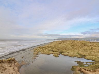 A coastal landscape with beach grass dunes a pond and waves at Ystwyth 26 in Borth