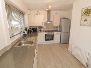 A kitchen with a stainless steel sink refrigerator oven cabinets and a painting of lemons at Seaside retreat in Porthmadog