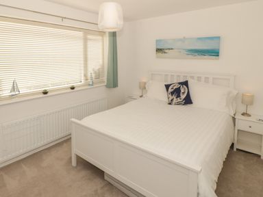 A bedroom with a white bed and nightstands with lamps at Seaside retreat in Porthmadog