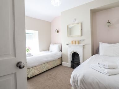 A bedroom with two single beds a small fireplace and a window at Artro View in Llanbedr