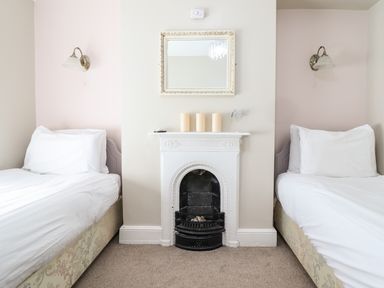 A bedroom with two single beds separated by a white decorative fireplace with candles and a mirror above at Artro View in Llanbedr