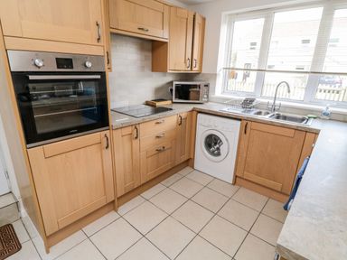 A kitchen with wooden cabinets built-in oven washing machine microwave and double sink at Crooked Well in Timsbury Nr Bath