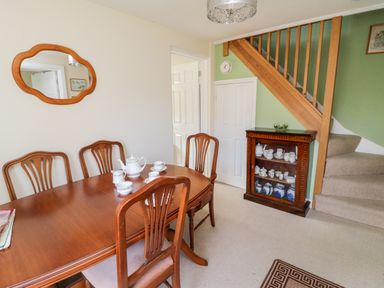 A dining room with wooden table and chairs tea set on table mirror on wall and cabinet under stairs at Crooked Well in Timsbury Nr Bath